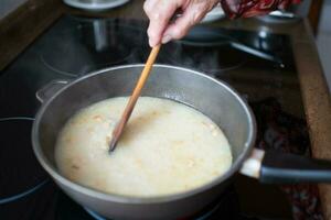 mayor mujer agitando arroz durante Cocinando foto