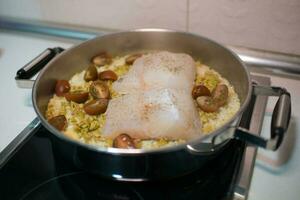 Close up of a cooking pot with rice, hake and cherry tomatoes photo