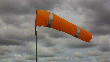 Windsock indicator of wind on tank chemical cone indicating wind direction and force. Horizontally flying windsock wind vane with cloud sky photo