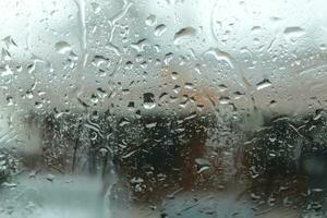 A close-up of the wet glass window of a motor vehicle, with raindrops and snow falling in the freezing indoor backgrounds. photo