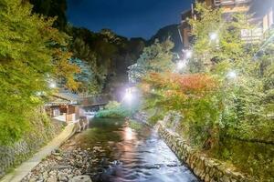 caliente primavera pueblos, kurokawa onsen, ryokan y puente a noche con Encendiendo llamarada, kurokawa, kumamoto, kyushu, Japón foto