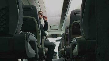 caucásico empresario vestido en traje sentado en autobús ajustando Gafas de sol torneado alrededor sonriente y hablando a otro pasajeros video