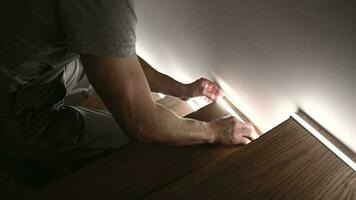 caucásico trabajador instalando LED de madera escalera Encendiendo. moderno Departamento iluminación. video
