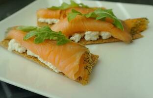 Healthy breakfast idea.Crisp with ricotta cheese, salmon and arugula on the top. photo