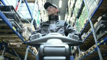 Kaukasisch pallet lifter operator arbeider in de magazijn opslag. video