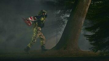 unido estados soldado en lleno uniforme corriendo a través de parque a noche con americano bandera flotante en su atrás. video