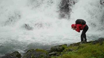 Wanderer Trinken Wasser Gerade von das Kristall klar Fluss. feuchtigkeitsspendend Körper auf das Weg video