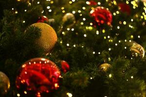 cerca arriba decoración pelota y ligero bulbo en Navidad árbol a noche foto