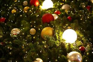 cerca arriba decoración pelota y ligero bulbo en Navidad árbol a noche foto