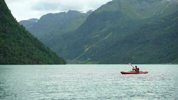 kajak resa på de sjö. caucasian män i de mitten av glacial- sjö i Norge. video
