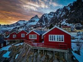 Red fishing cabins in Lofoten Norway in sunset by drone, Snow mountains photo