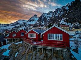 rojo pescar cabañas en lofoten Noruega en puesta de sol por zumbido, nieve montañas foto