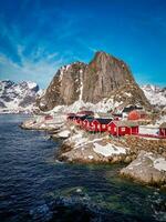 Red fishing cabins in Lofoten Norway by drone, rorbuer snow mountain photo