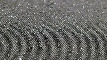 spinning background of black hydrophobic fabric while covering with water drops video
