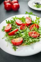 plate of salad tomato, arugula, grated cheese, olive oil healthy meal food snack on the table copy space food background rustic top view keto or paleo diet veggie vegan or vegetarian food no meal photo