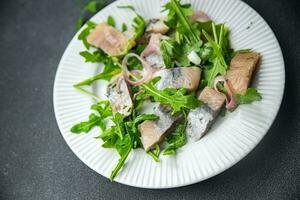 herring pieces pickled onion, green arugula leaves meal food snack on the table copy space food background rustic top view  pescatarian diet photo