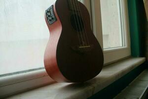 Ukulele guitar leaning against window as it finishes playing, May 7, 2023 Turkey photo