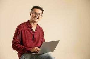 Simple young freelancer sitting working on laptop pc computer looking isolated on bright colored wall, studio photo background.