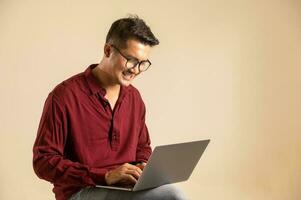 Simple young freelancer sitting working on laptop pc computer looking isolated on bright colored wall, studio photo background.