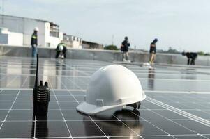 Solar installation concept White helmet blueprint and walkie talkie on solar panel High security wearing helmet at work site installing solar panels on the roof photo