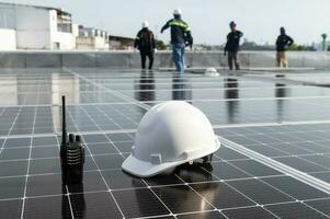 Solar installation concept White helmet blueprint and walkie talkie on solar panel High security wearing helmet at work site installing solar panels on the roof photo