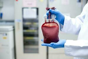 Doctor's hand holding blood bag in laboratory technician analyzing blood bag in blood bank photo