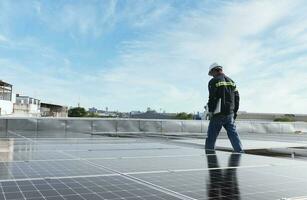 technician inspecting solar panels on factory roof Check and maintain the solar panel roof A team of technicians installing solar panels on the roof of a high-rise building photo