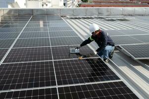 technician inspecting solar panels on factory roof Check and maintain the solar panel roof A team of technicians installing solar panels on the roof of a high-rise building photo