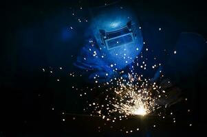 Asian worker wearing industrial uniform and welding mask at welding factory Safety concepts in the small factory industry. photo