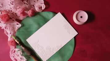 Top View of Beige Luxury Invitation Card with Feather on Floral Red And Green Silk Background. . photo