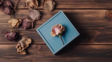 Top View of Blue Closed Box and Dried Rose Flowers on Wooden Table. . photo