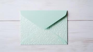 Isolated Pastel Green Customized Floral Embossed Luxury Wedding or Event Card, Envelope on White Wooden Background and Space for Message. . photo