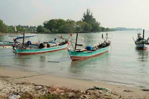 Fishing boats on the beach during morning fog on the water photo