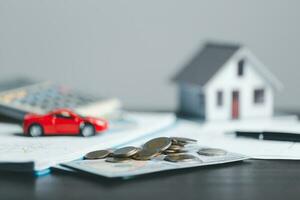 Car and house model with coins and financial document on wooden table. Asset approval concepts purchases to buy a car and a house. Ideas for home buying checklist home loan tax photo