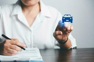 Business woman's hand protecting blue icon car on desk. Planning to manage transportation finance costs. Concept of car insurance business, saving buy - sale with tax and loan for new car. photo