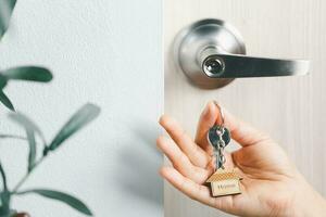 close up key on the door with morning light, personal loan concept. House model and key in house door. Real estate agent offer house, property insurance and security, affordable housing concepts. photo