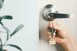 close up key on the door with morning light, personal loan concept. House model and key in house door. Real estate agent offer house, property insurance and security, affordable housing concepts. photo