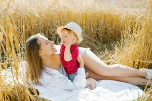 A happy mother and her little son are lying on a blanket at a picnic. Funny sweet family moments in the field outdoors photo