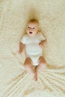 Cute charming white Caucasian boy with blue eyes lying on the bed smiling at the camera. View from above. A happy lifestyle in childhood. photo