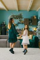 Mom and daughter holding hands in the living room of the house, decorated for Christmas photo