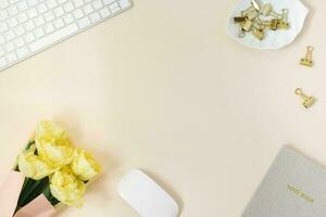 Flat lay blogger or freelancer workspace with Notepad, keyboard and a bouquet of yellow peony tulips photo