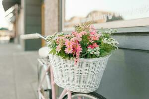 artificial flores en el cesta de un de madera bicicleta cerca el ciudad café foto