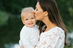 un madre Besos su dos años de edad hijo. el hijo es contento y sonriente. de la madre día foto