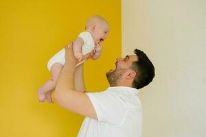 Positive cheerful dad holds his son in his arms. Happy parent and baby photo