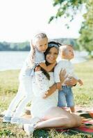 hijo y hija abrazo su madre. verano picnic en naturaleza foto