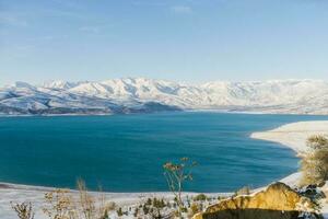 Charvak reservoir in Uzbekistan in winter with blue water in it, surrounded by the Tien Shan mountain system photo