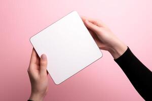 white blank notepad in female hands on a pink background photo