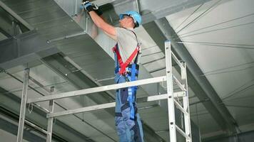 construcción trabajador en andamio adjuntando y atornillar metálico partes de ventilación conducto sistema. video