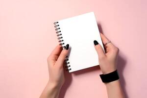 white blank notepad mockup in female hands on a pink background photo