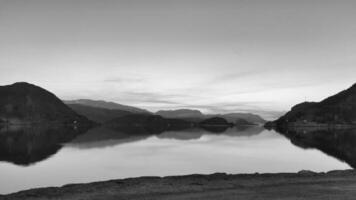 Fjord with view of mountains and fjord landscape in Norway in black and white photo